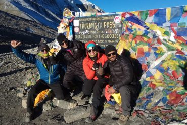 Lead guide Ajit at Thorong La Pass with group of trekkers