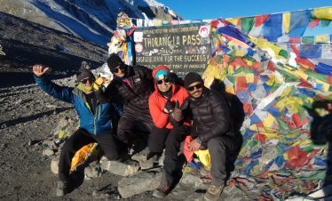 Lead guide Ajit at Thorong La Pass with group of trekkers