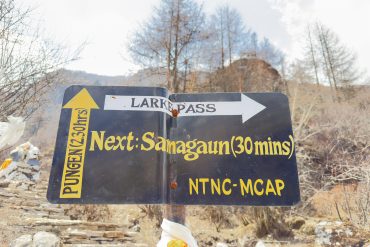 Trail sign near Samagaun pointing toward Larke Pass and Pungen on the Manaslu Circuit Trek in Nepal.
