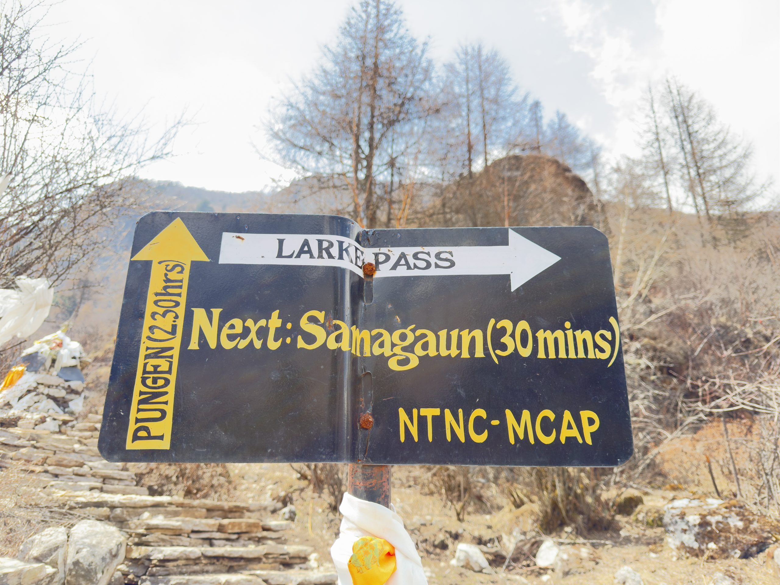 Trail sign near Samagaun pointing toward Larke Pass and Pungen on the Manaslu Circuit Trek in Nepal.
